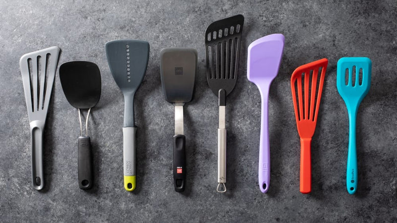 Eight different colors and sizes of spatulas lined up next to another