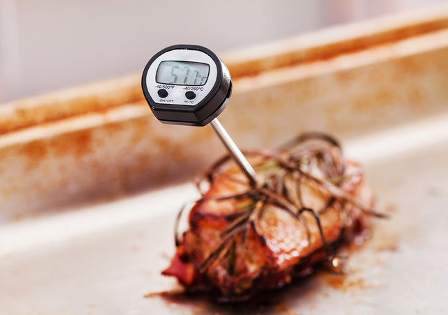 A meat thermometer reading "57.5" in a piece of meat